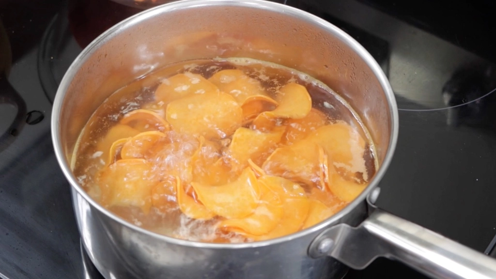 Pot of boiling water with sweet potato chips in it.