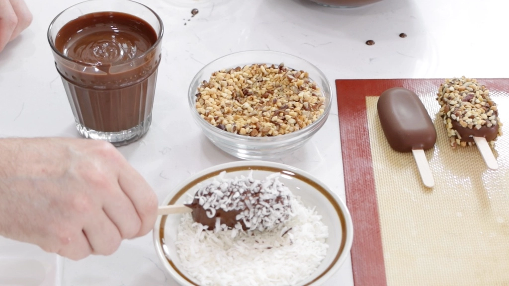 Ice Cream Bars Recipe | 5 Ingredients - In The Kitchen With Matt 8 Hand dipping an ice cream bar in coconut flakes.