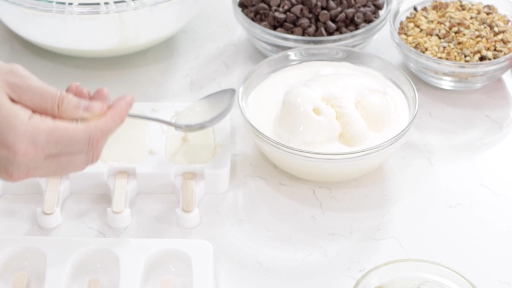 Ice Cream Bars Recipe | 5 Ingredients - In The Kitchen With Matt 3 Hand with ladle filling up a popsicle mold with ice cream base.