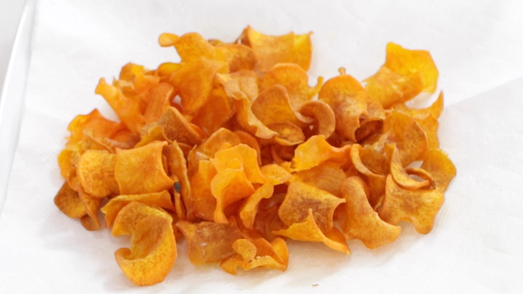 Finished sweet potato chips on a plate with paper towel.