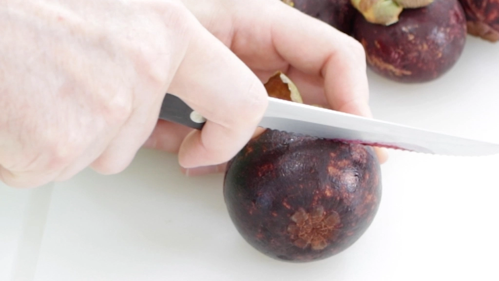 Hand cutting a mangosteen around its equator.