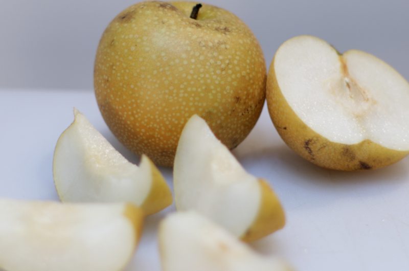 Sliced Asian Pear on a white cutting board.