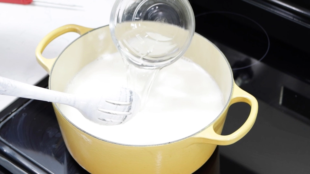 Pouring vinegar into a pot with hot milk.