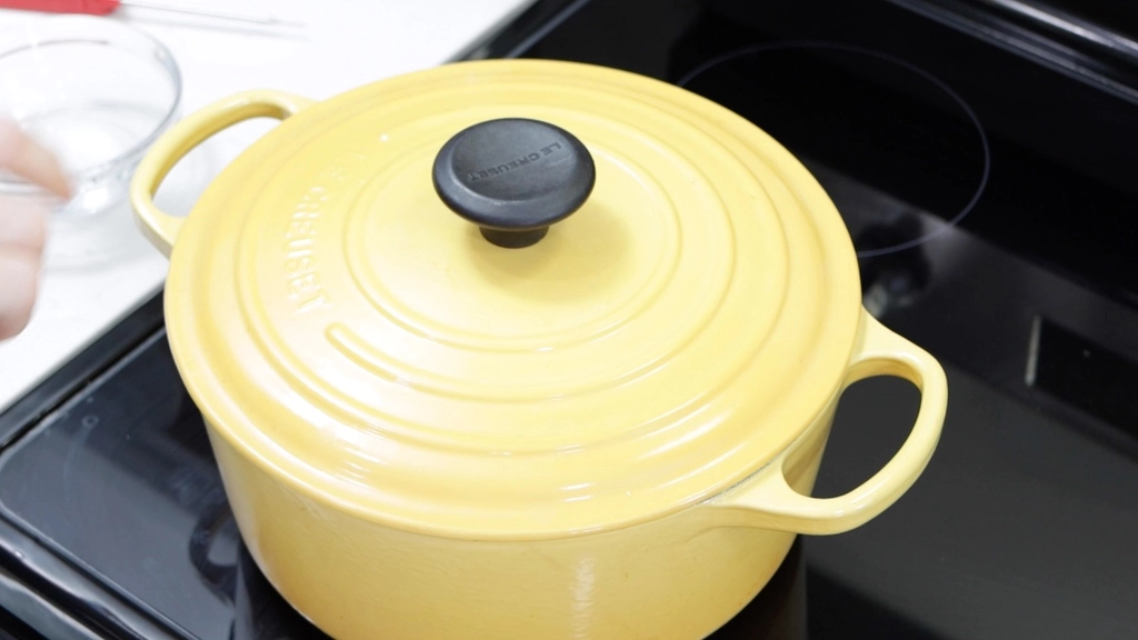 Lid on top of a yellow pot of homemade mozzarella cheese.
