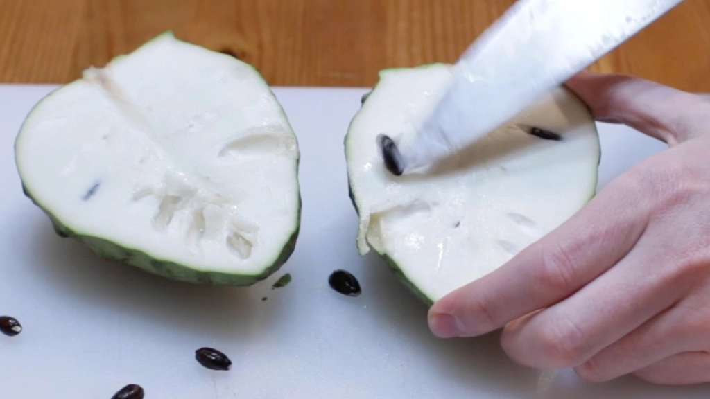Knife cutting out the seeds of a cherimoya.