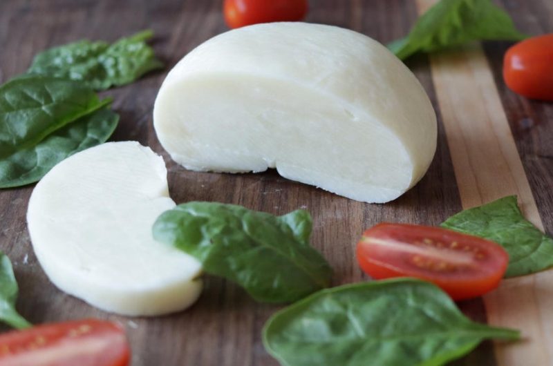 Fresh homemade mozzarella cheese from milk powder on a cutting board.
