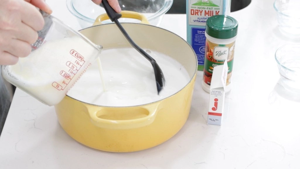 Pouring buttered milk into pot of milk.