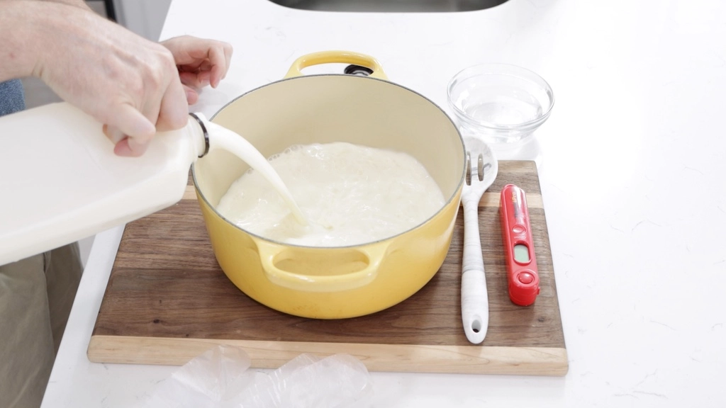 Raw milk being poured into a large yellow pot.