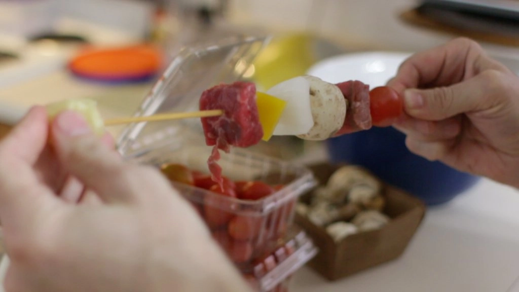 Hands holding beef kabob.