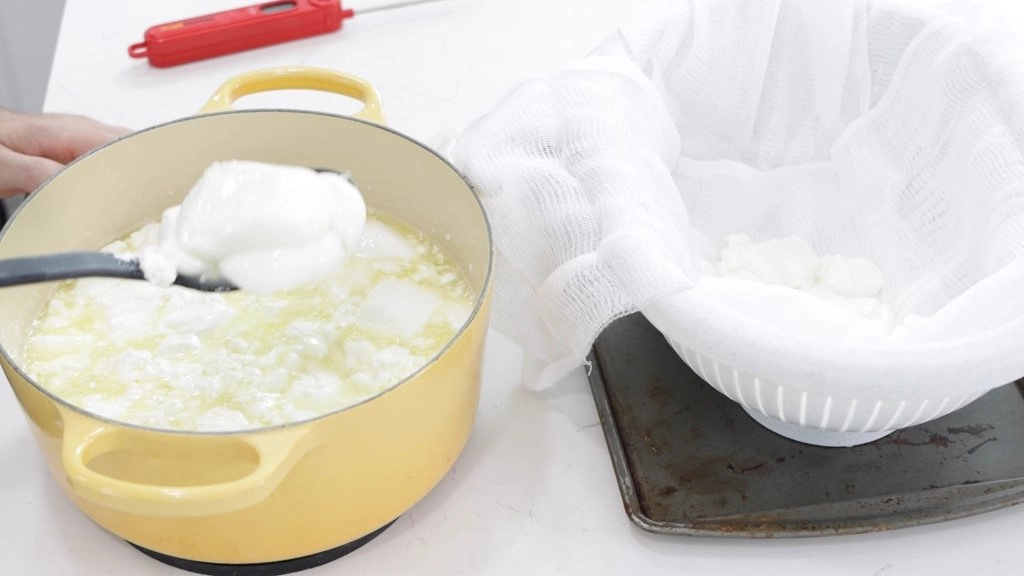 Spoon separating the mozzarella cheese curd from the whey