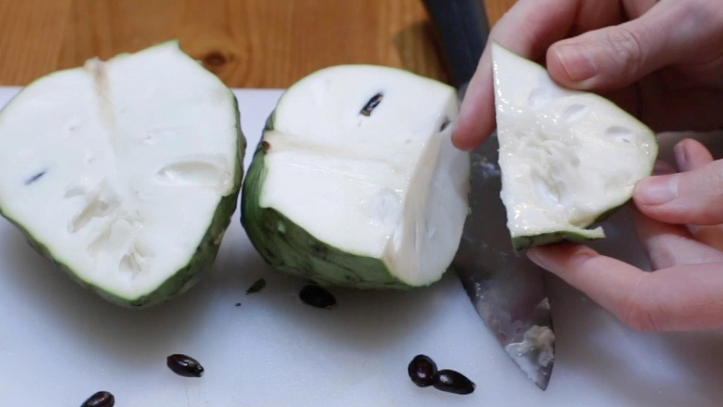 Hand holding a chunk of cherimoya.