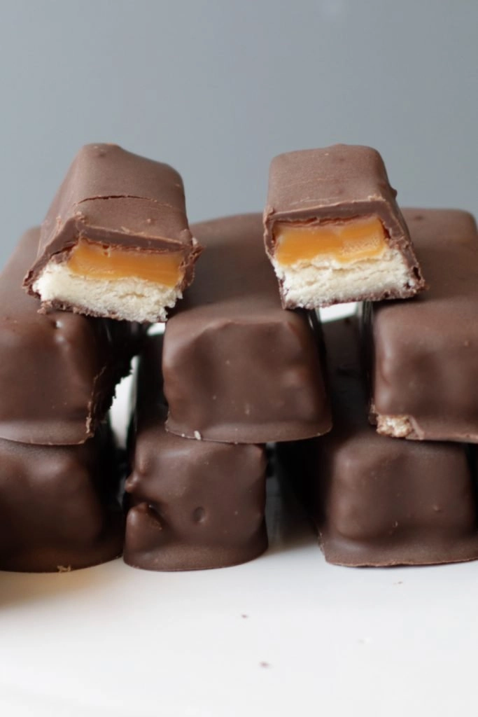 Homemade Twix bars piled up on a white plate.
