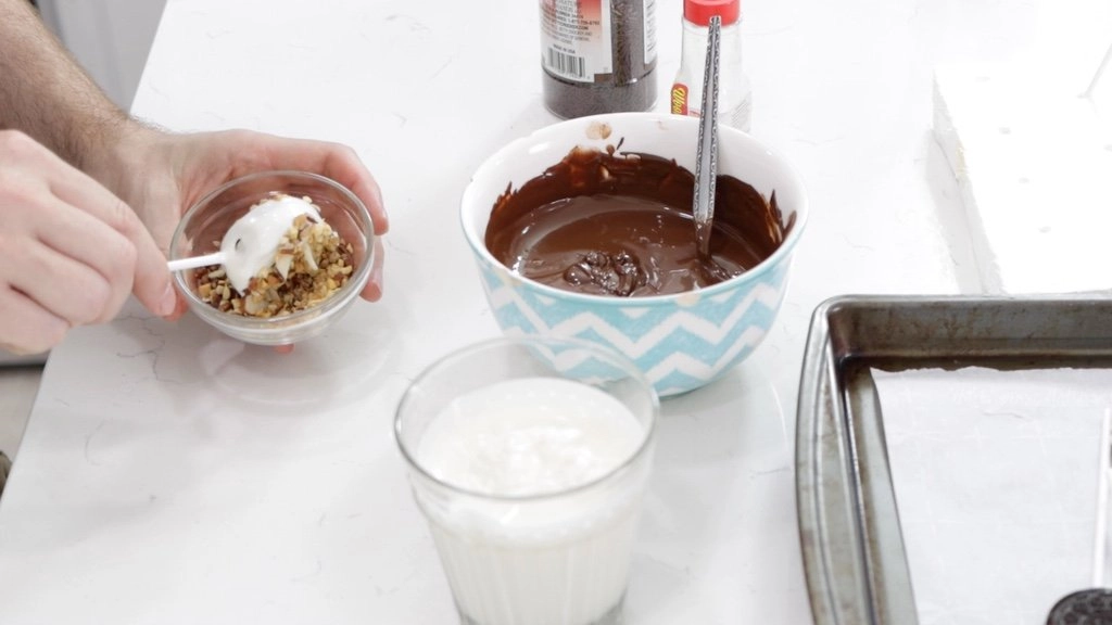 Oreo pop beging dipped in nuts.