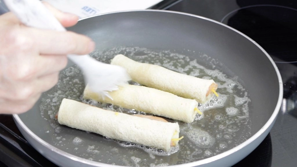 Grilled cheese roll ups in a skillet with butter.