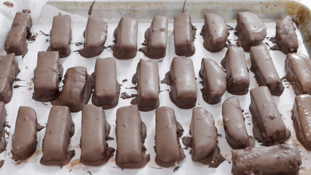 Dipped homemade Twix bars on a sheet pan with parchment paper.