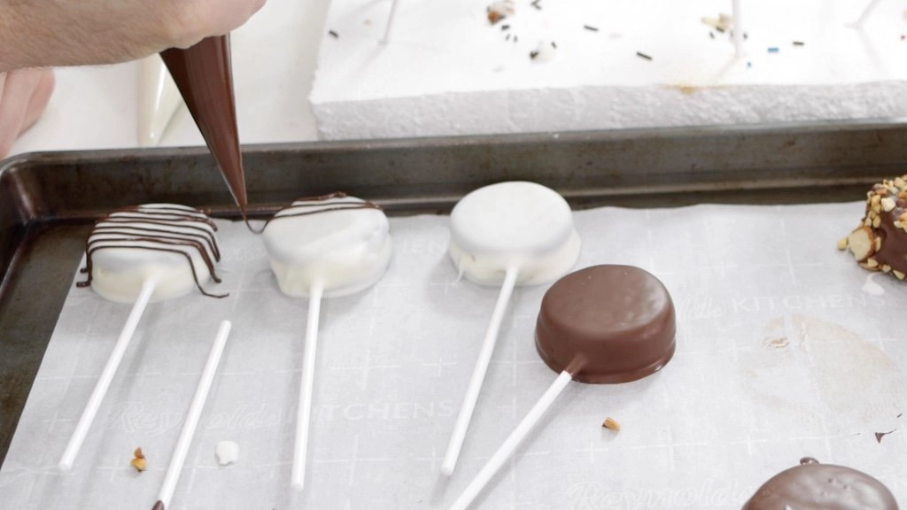Drizzling chocolate on white Oreo pops.