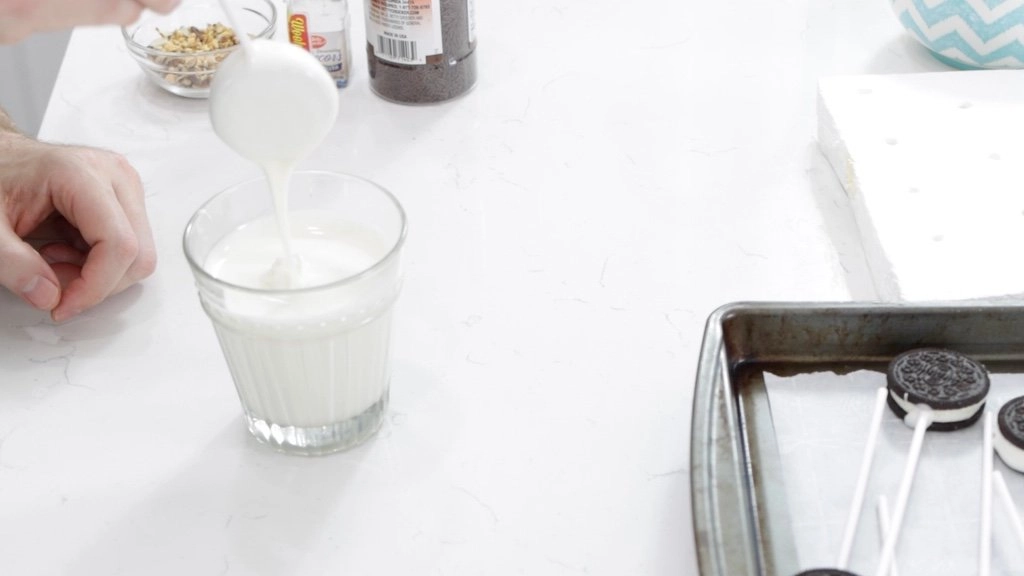 Hand dipping Oreo pops in white chocolate.