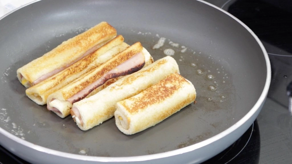 Cooked grilled cheese roll ups in a skillet.