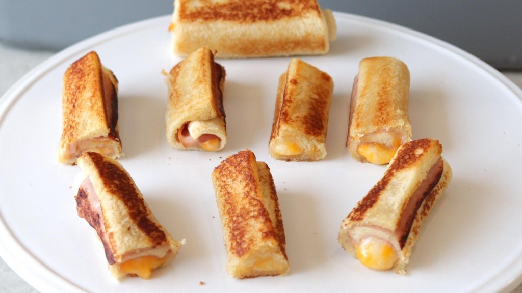 Finished grilled cheese roll ups on a white plate.