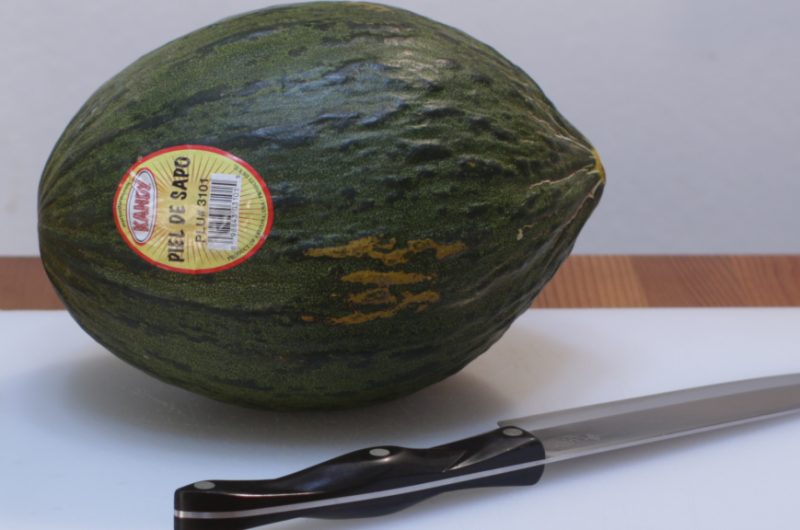 Santa claus melon on a cutting board next to a knife