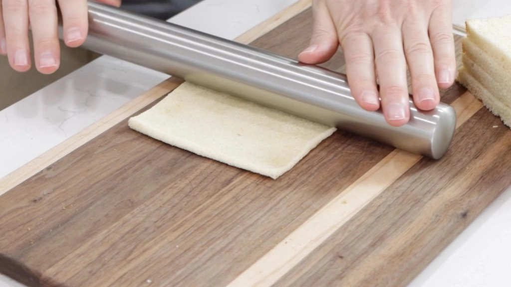 Hand rolling out the bread on a cutting board. Hand rolling out the bread on a cutting board.