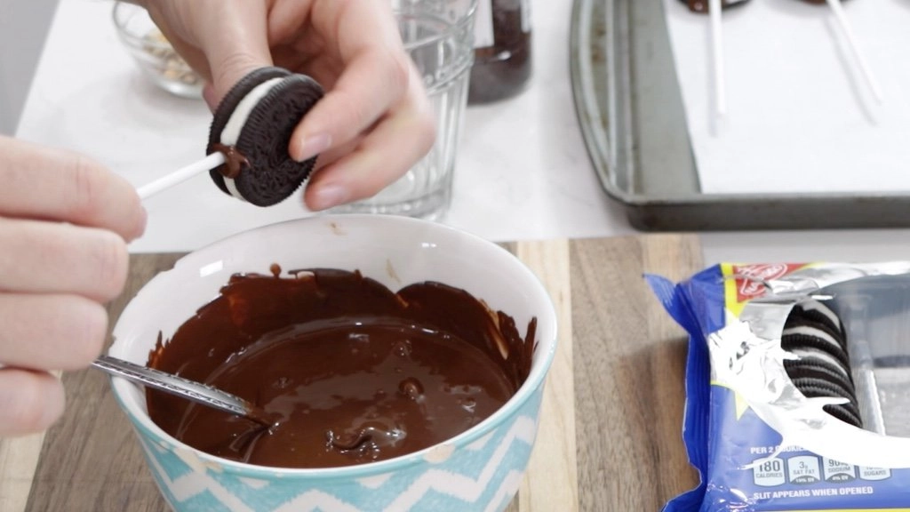 Hand placing a white treat stick in a megastuff Oreo.