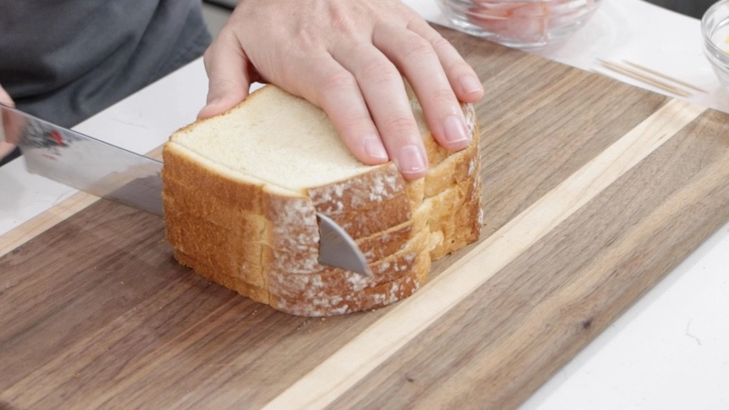 Knife slicing the crust off of white bread. Knife slicing the crust off of white bread.