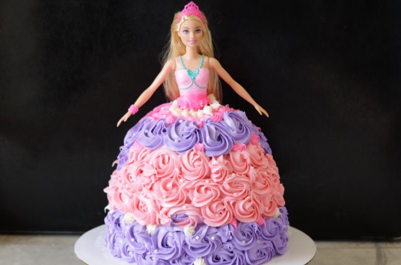 Barbie cake on a white cake pedestal.