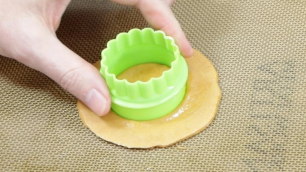 Hand press green round cooking cutter into dalgona candy