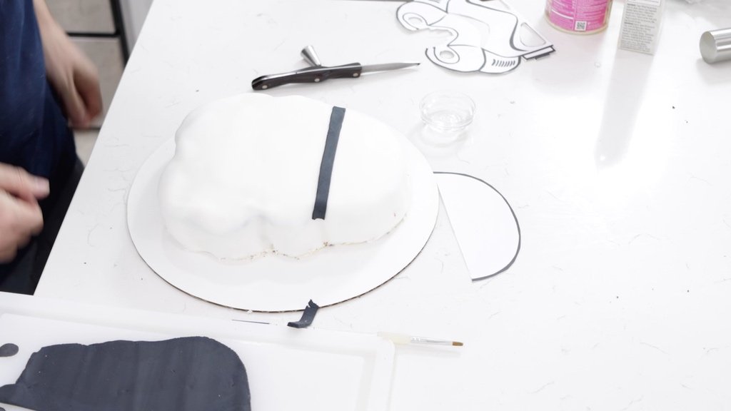 Black ban of fondant on the head of the white cake.