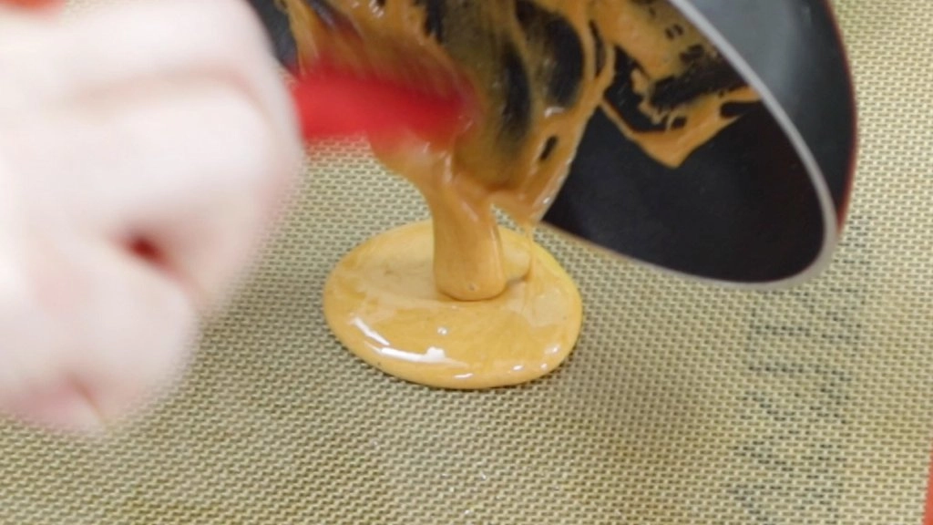 Pouring the Squid Game candy onto a silicone baking mat.