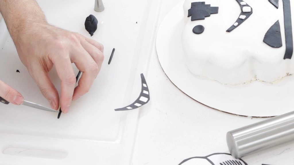 Hand cutting a thin black fondant snake into pieces