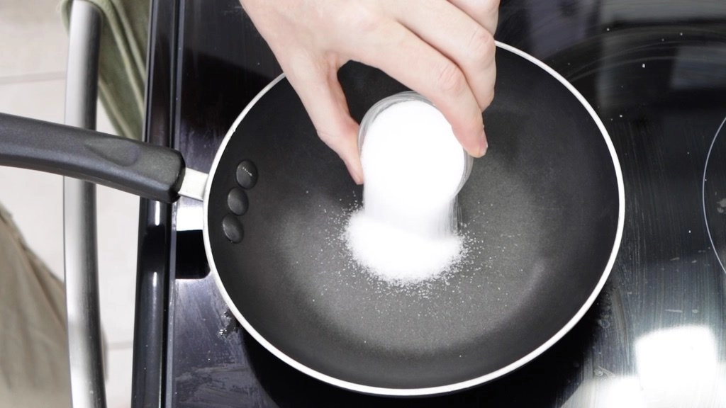 Pouring sugar onto a small skillet.