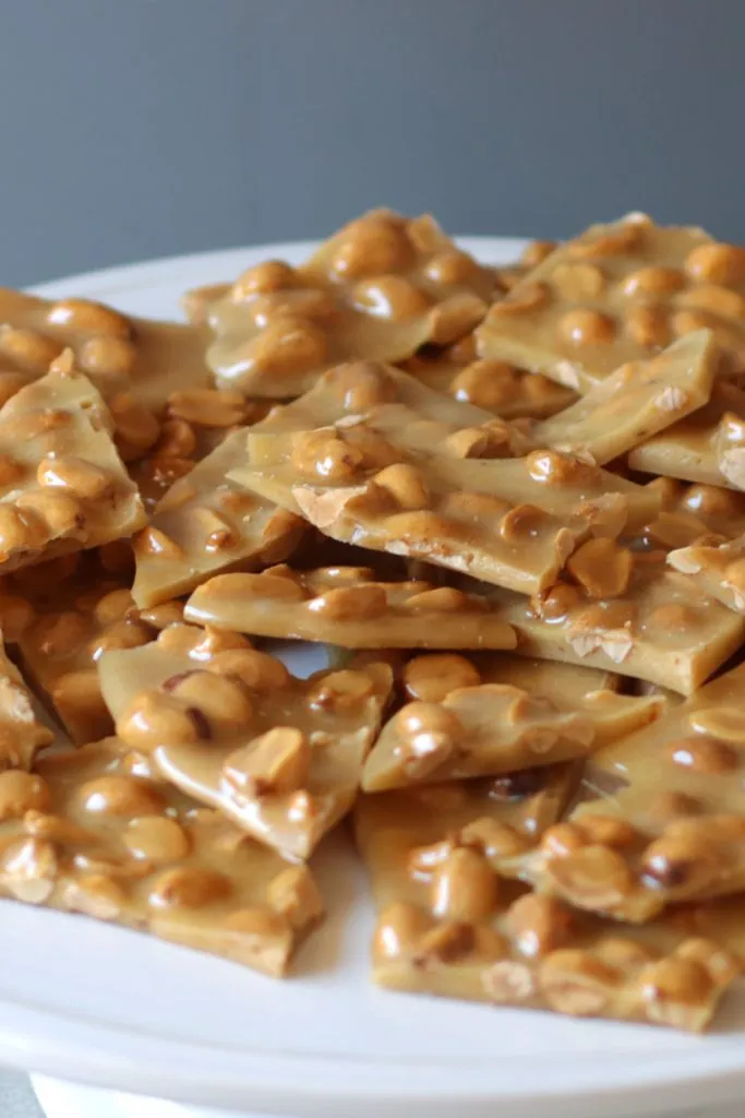Large pile of peanut brittle on a white plate.