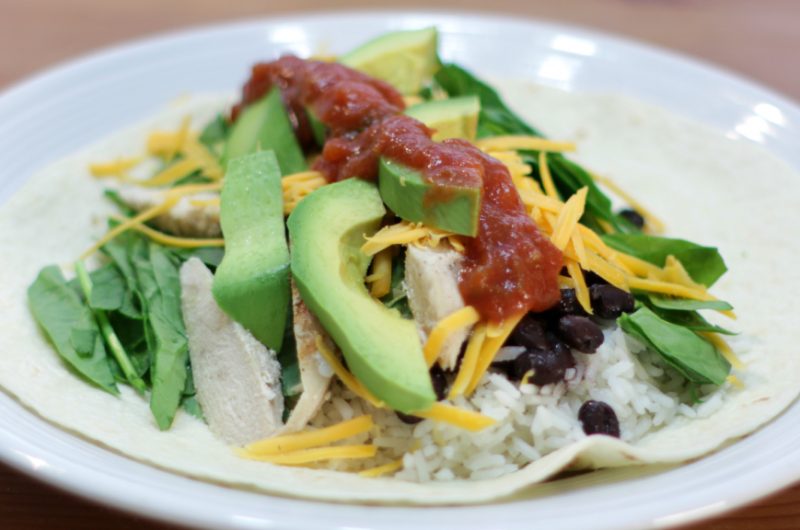 Open faced chicken burrito on a white plate