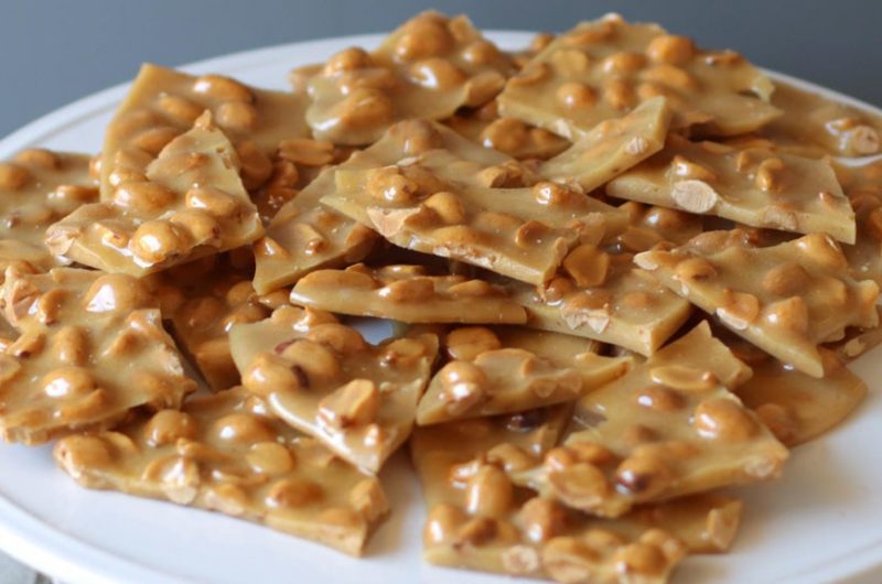 pile of classic peanut brittle on a white plate.