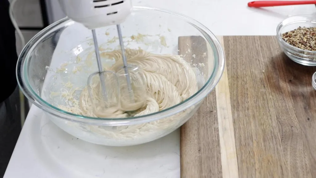 Hand mixer creaming butter, sugar, and vanilla extract in a bowl