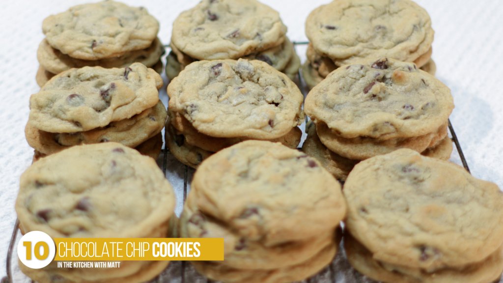 Stacks of homemade chocolate chip cookies on a wire cookie rack. 