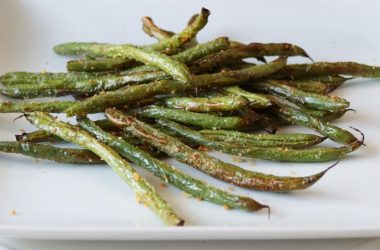 Pile of air fryer green beans on a white plate.