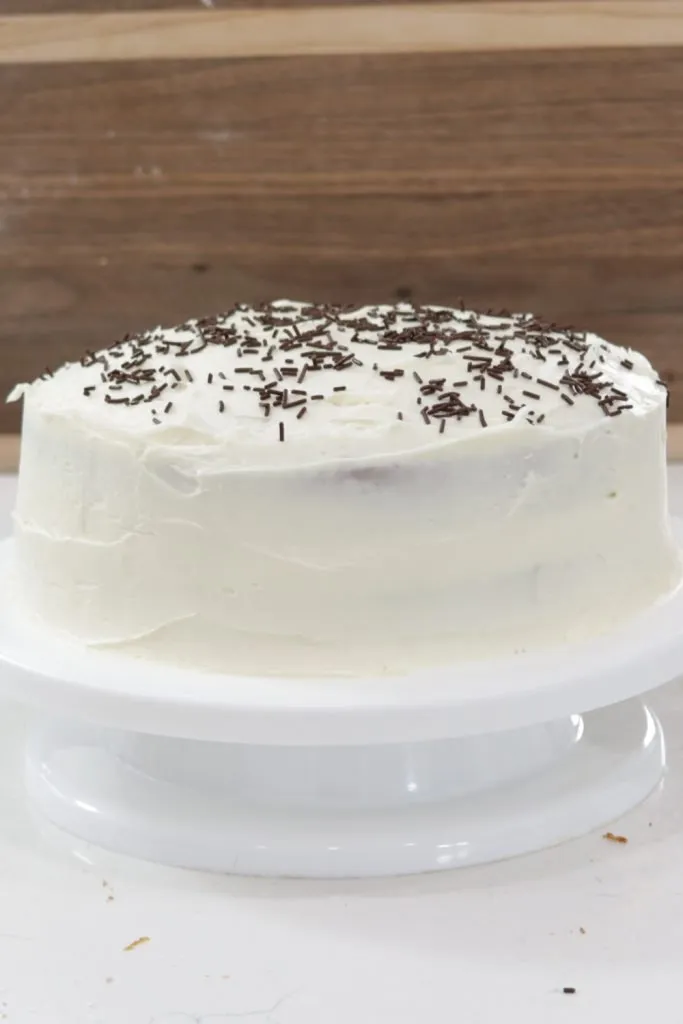 Vanilla cake on a white cake pedestal.