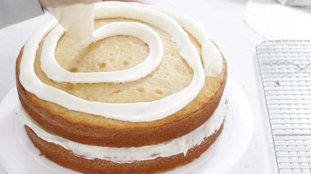 Frosting and layering a vanilla cake.