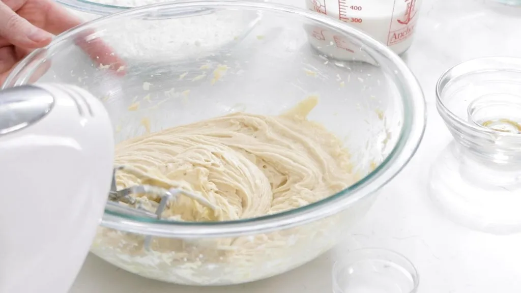 Wet vanilla cake ingredients creamed together in a large glass bowl.