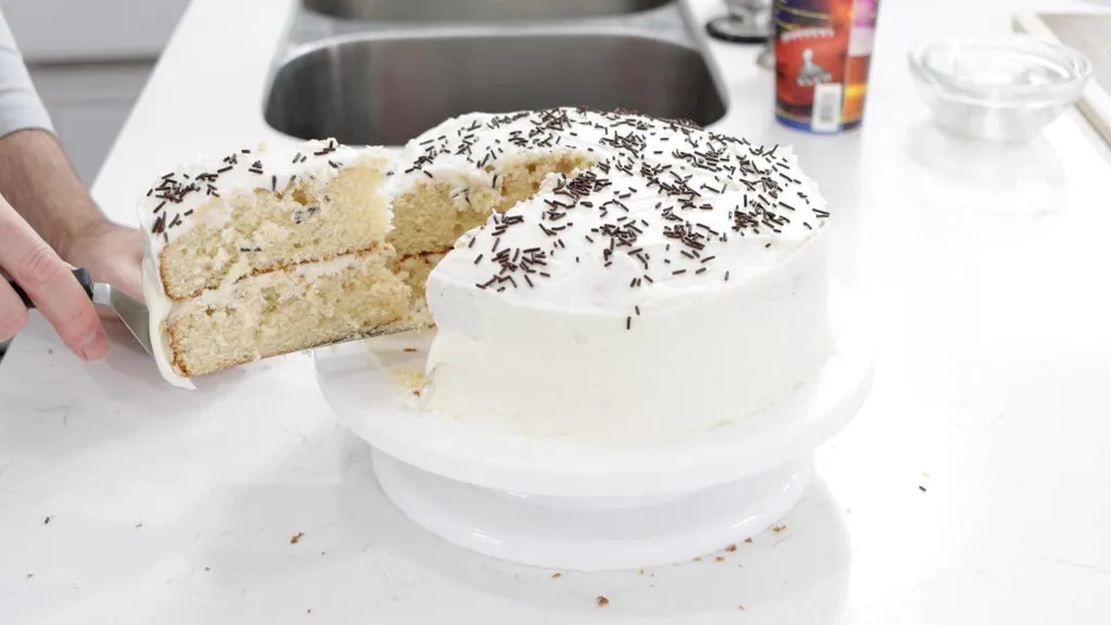Slice of vanilla cake next to a the full cake.