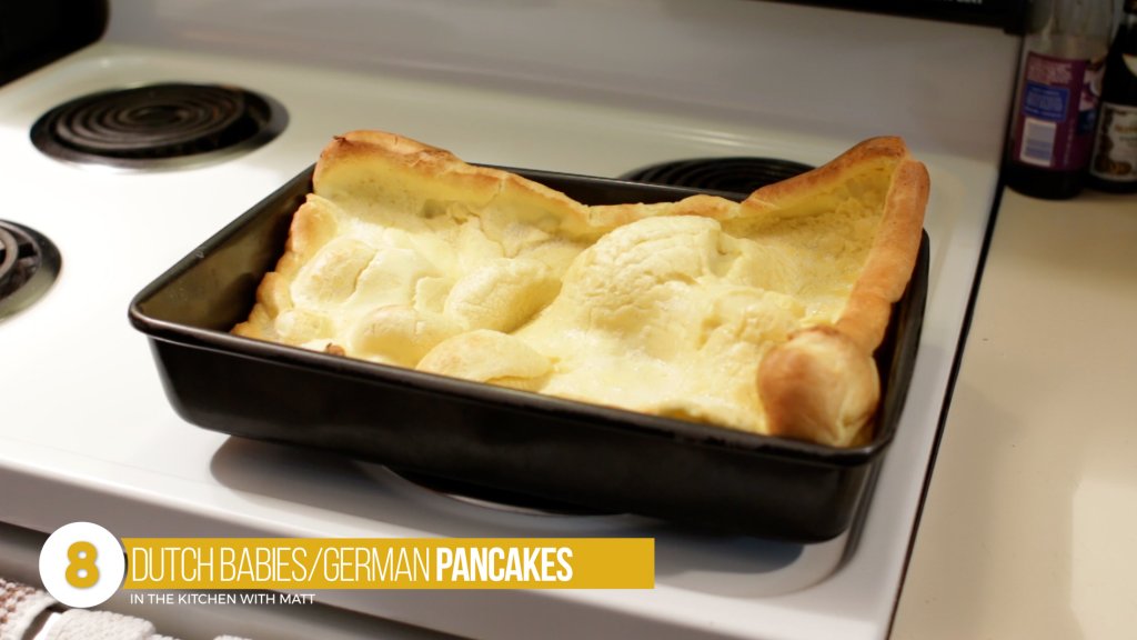 Large dutch baby or German pancake in a baking pan on top of an oven burner.