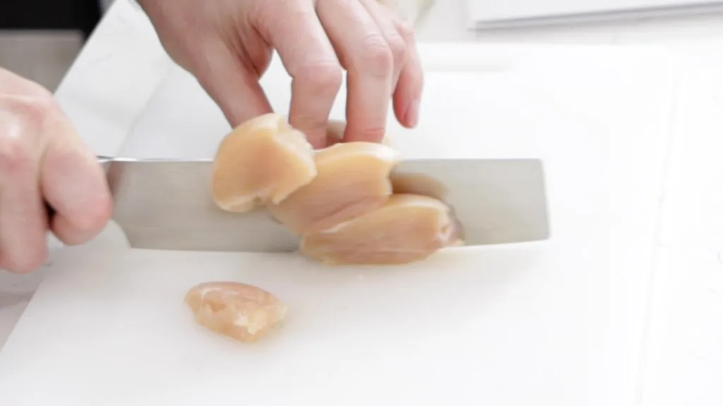 Knife cutting through a thick chicken breast.