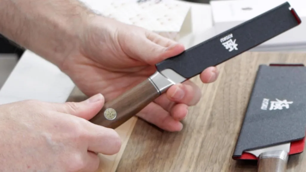 Hand holding a Kyoku knife with the guard on it.
