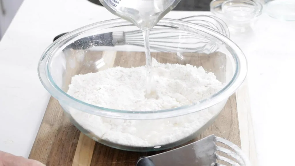 Water being added to the bowl of dry ingredients. 