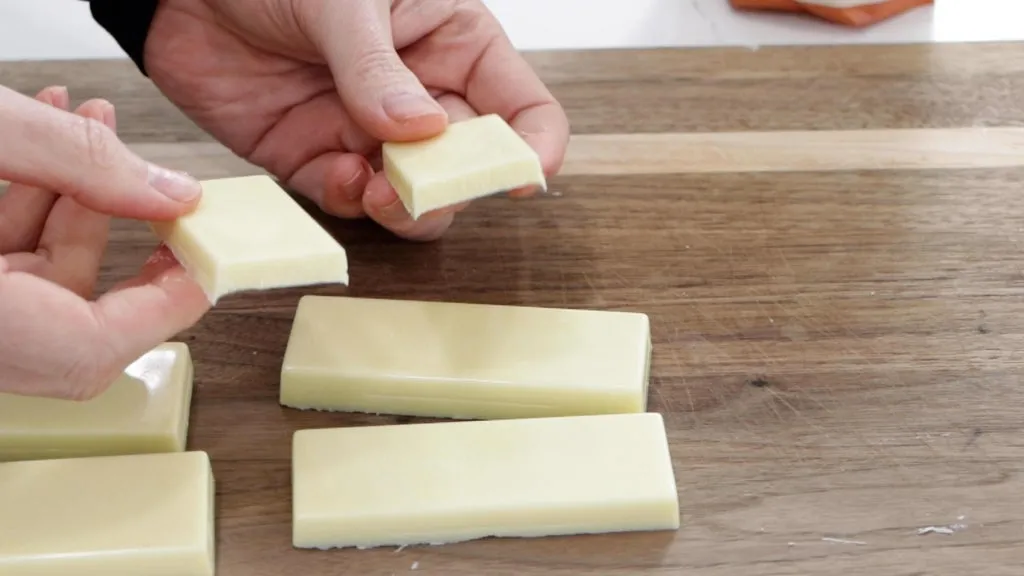 Hand holding two pieces of white chocolate