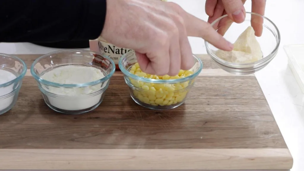Cocoa butter in glass bowls on a wooden cutting board.