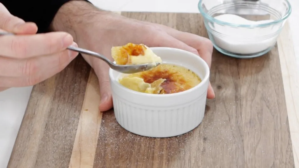 Hand with a spoonful of homemade creme brulee